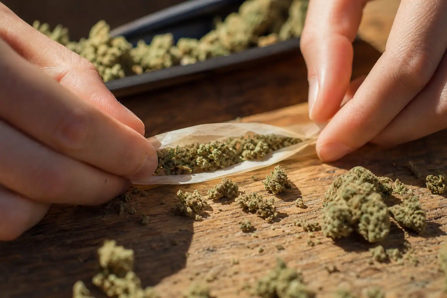 Des mains préparent quelque chose, autour de wnba retire cannabis, près d'une table en bois.